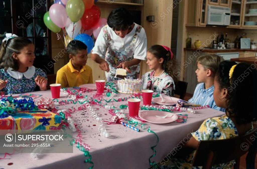 Stock Photo: 295-655A Mid adult woman serving children cake at a birthday party