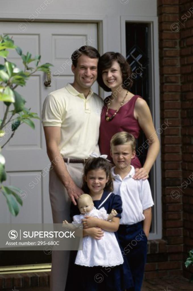 Stock Photo: 295-680C Mid adult couple standing with their children in front of a house