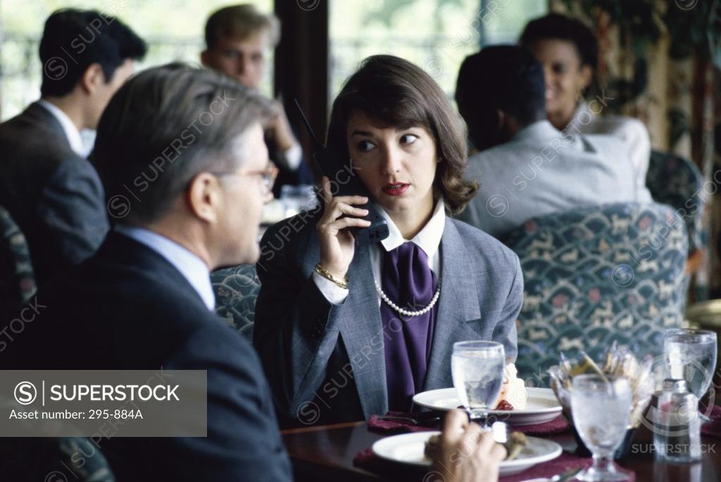 Stock Photo: 295-884A Businesswoman using a cordless phone and a businessman sitting beside her in a restaurant