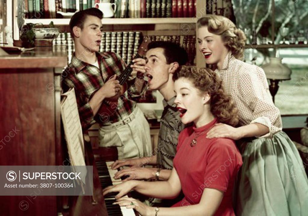 Stock Photo: 3807-100364 Teenage couple playing a piano with another teenage couple standing near them