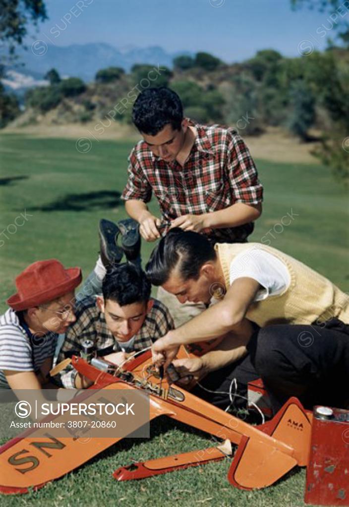 Stock Photo: 3807-20860 Four teenager boys repairing a model airplane in a park
