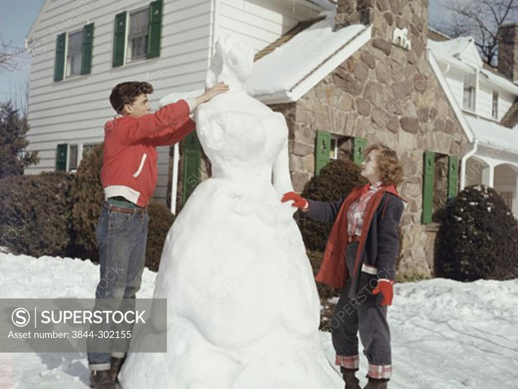 Stock Photo: 3844-302155 Side profile of a teenage couple making a sculpture of snow