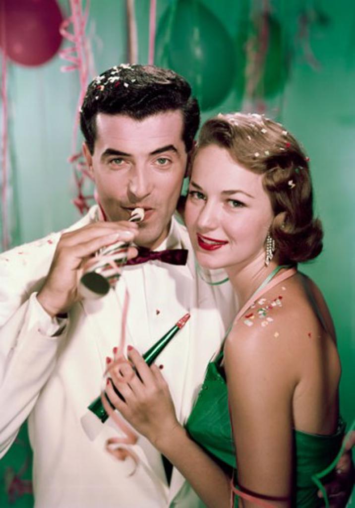 Portrait of young couple with party horn blowers