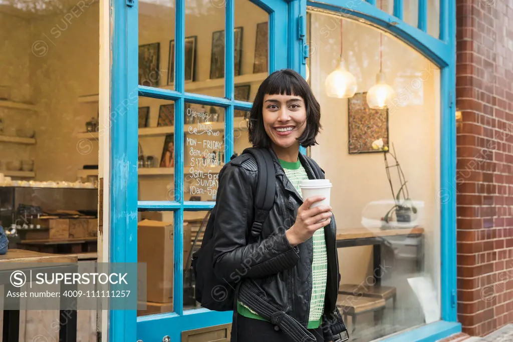 Woman walking out of cafe with coffee in hand