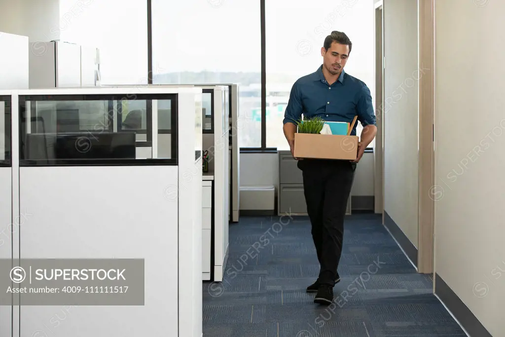 A man walks out of his office with a box of his personal belongings