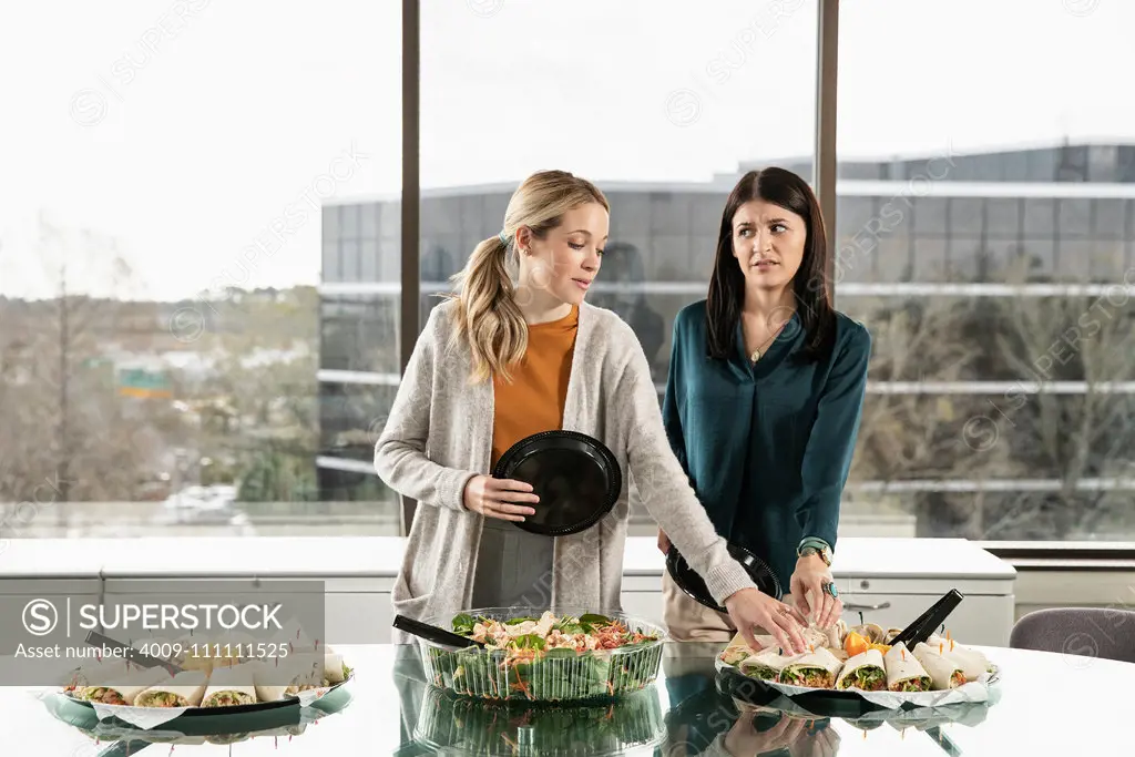 Two people reaching for the same item on a lunch buffet.