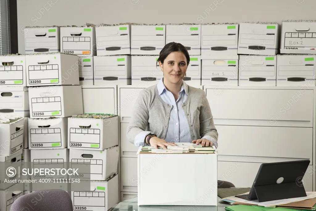 Portrait of a woman surrounded by boxes of office files.