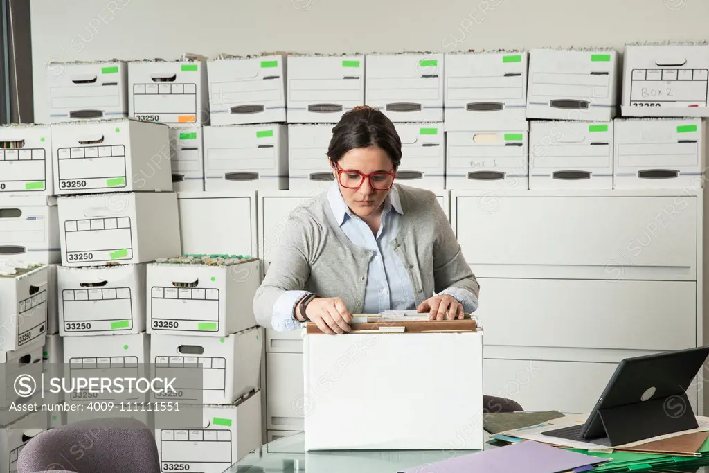 Young employee sorts through files in her office