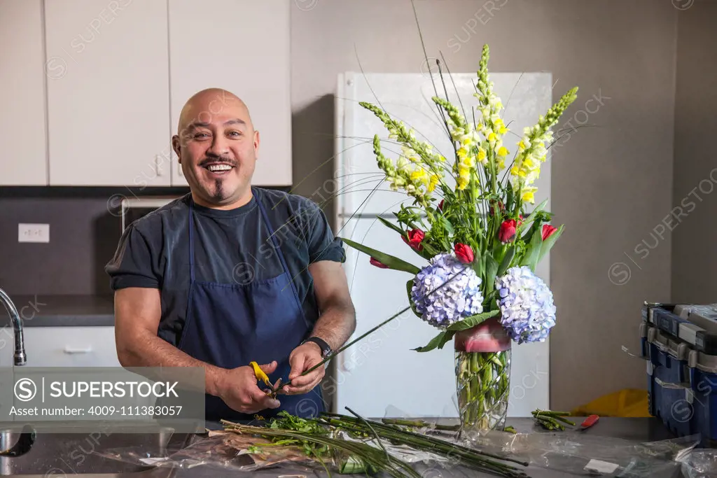 Smiling man arranging flowers in kitchen