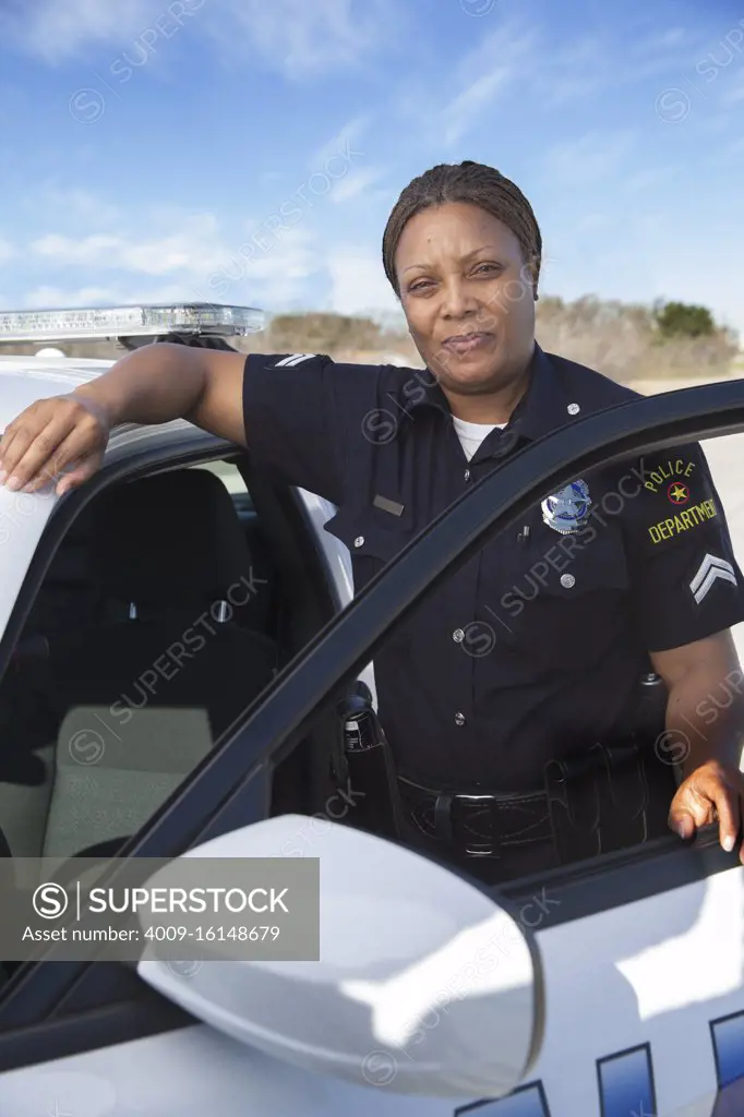Policewoman standing in door of Police car looking towards camera 