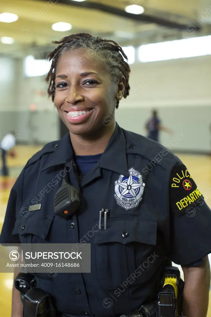 Portrait of Police woman standing in gymnasium looking towards camera smiling 