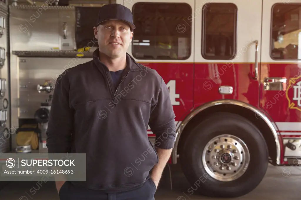 Portrait of Fireman standing in front of firetruck with hands in pockets