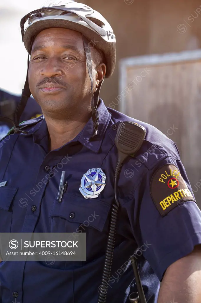 Portrait of Bicycle Police officer standing outside looking towards camera smiling 