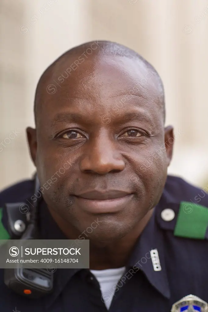 Close up Portrait of uniformed Police officer sitting outside looking towards camera smiling 