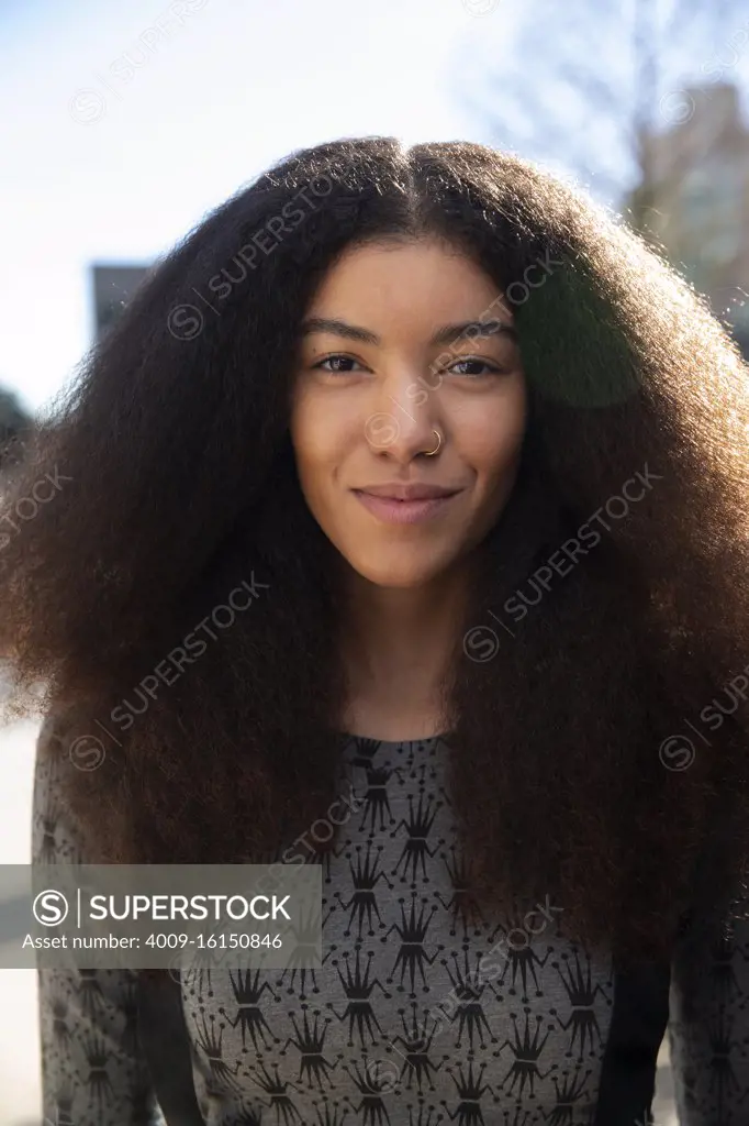 Portrait of woman with long hair standing outside, looking at camera 