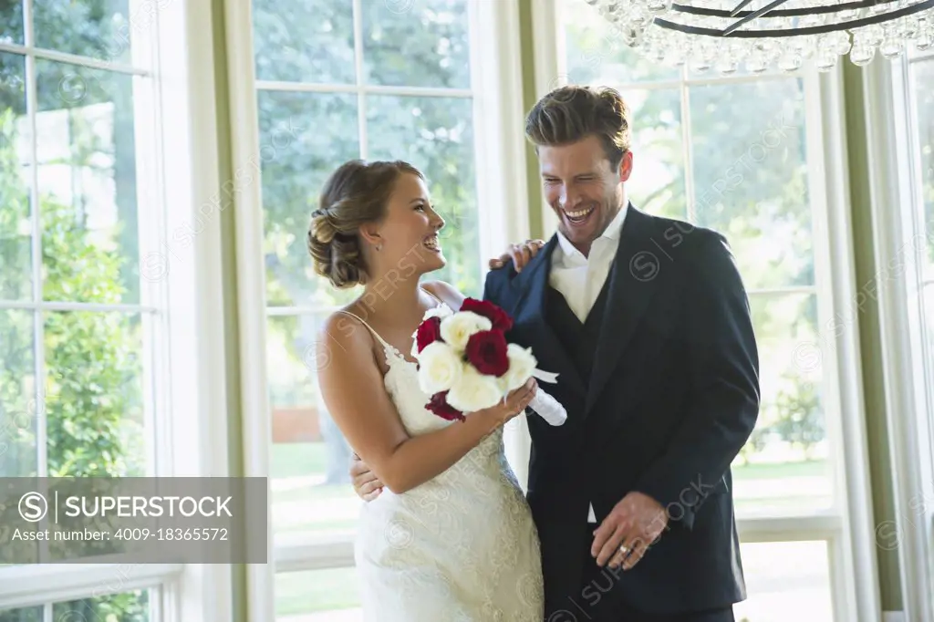 Bride and Groom walking into reception,  laughing and looking down, bride holding bouquet 