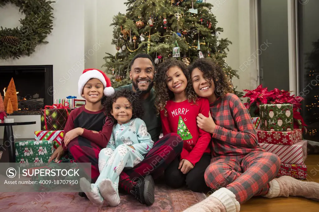 Christmas Card Portrait of a joyful young Black family sitting in front of Christmas tree