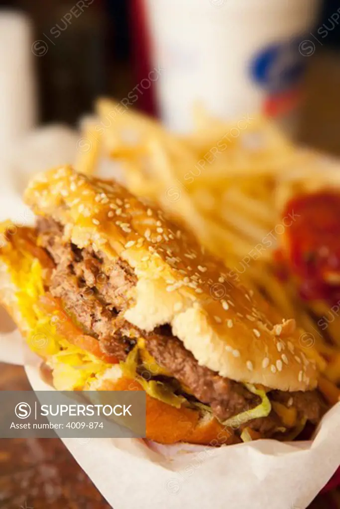 Close-up of a half eaten hamburger with fries in the background