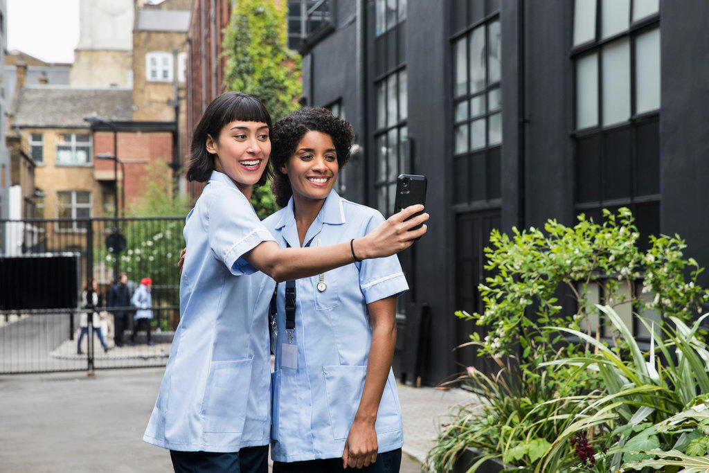 Women in healthcare industry taking selfie in alley