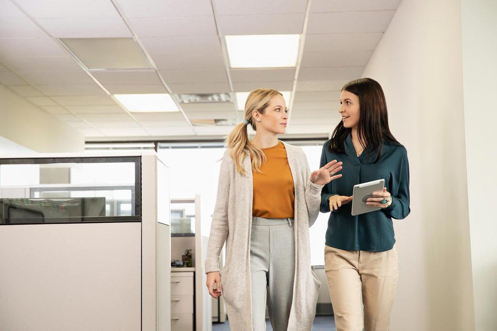 Two co-workers walking together in an office