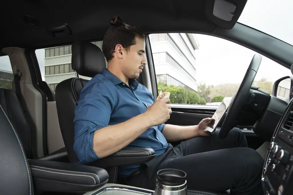 Man eating lunch in his car while using a tablet