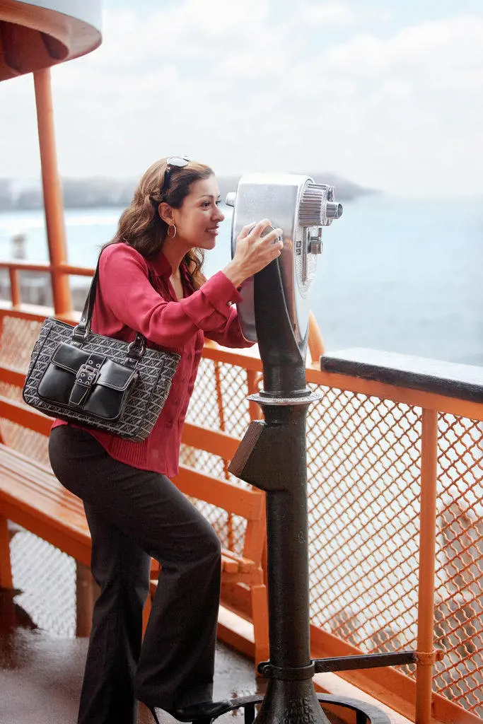 Hispanic businesswoman looking through binoculars on ferry