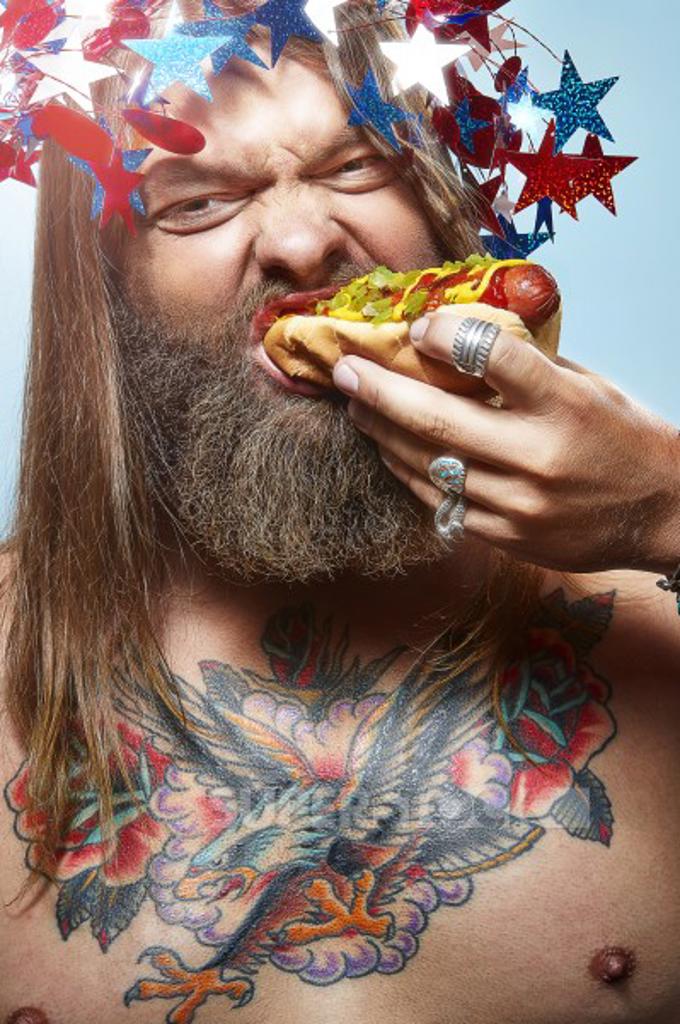 Portrait of a man dressed up for the 4th of July eating a hotdog