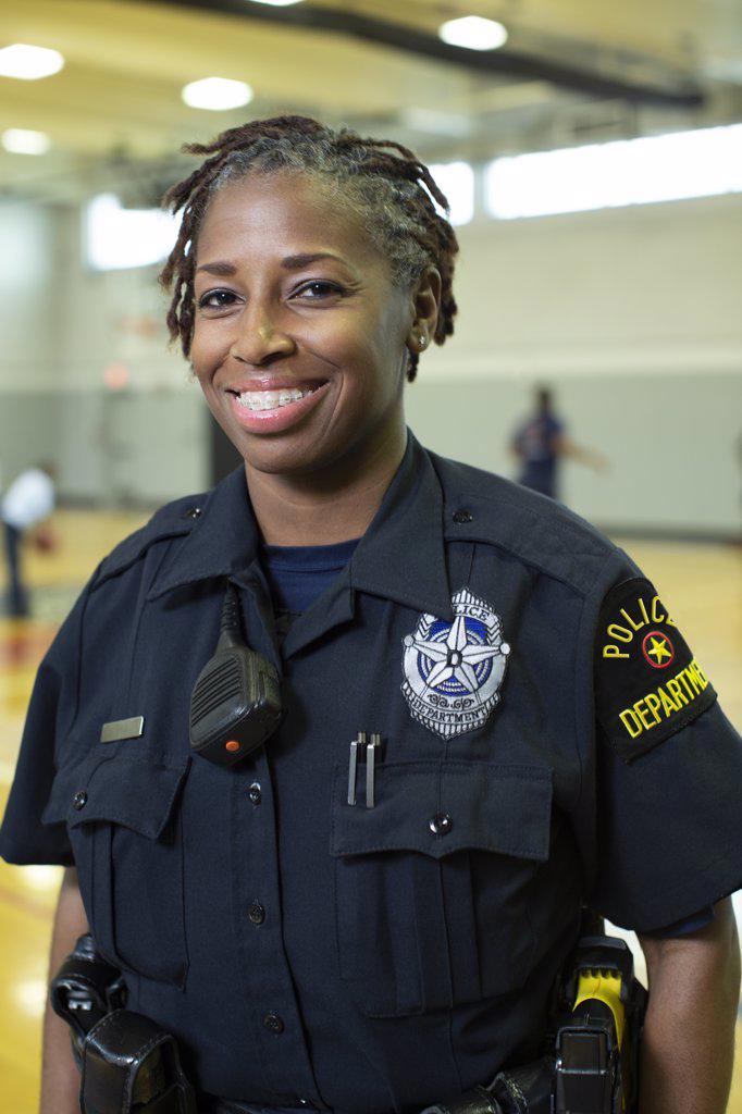 Portrait of Police woman standing in gymnasium looking towards camera smiling 