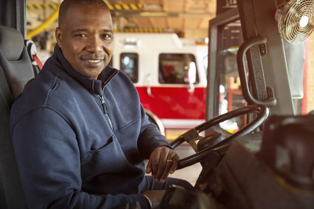 Portrait of Fireman Sitting in Drivers seat of firetruck looking towards camera  smiling 