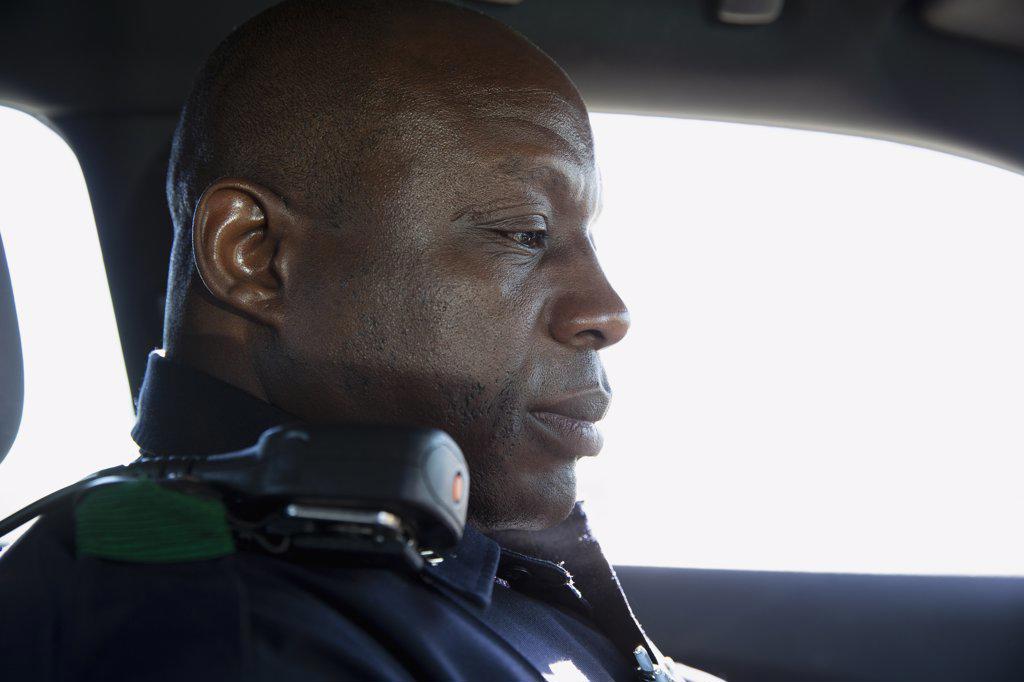 Close up Portrait of uniformed Police officer sitting in squad car looking towards in car computer
