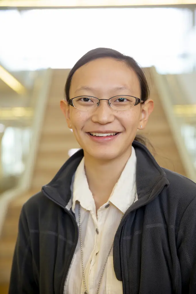 Portrait of young ethnic woman standing in lobby of building, smiling looking towards camera 