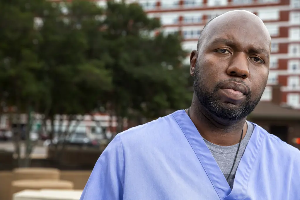 Portrait of middle aged man  with beard and a bald head wearing scrubs standing outside looking at camera