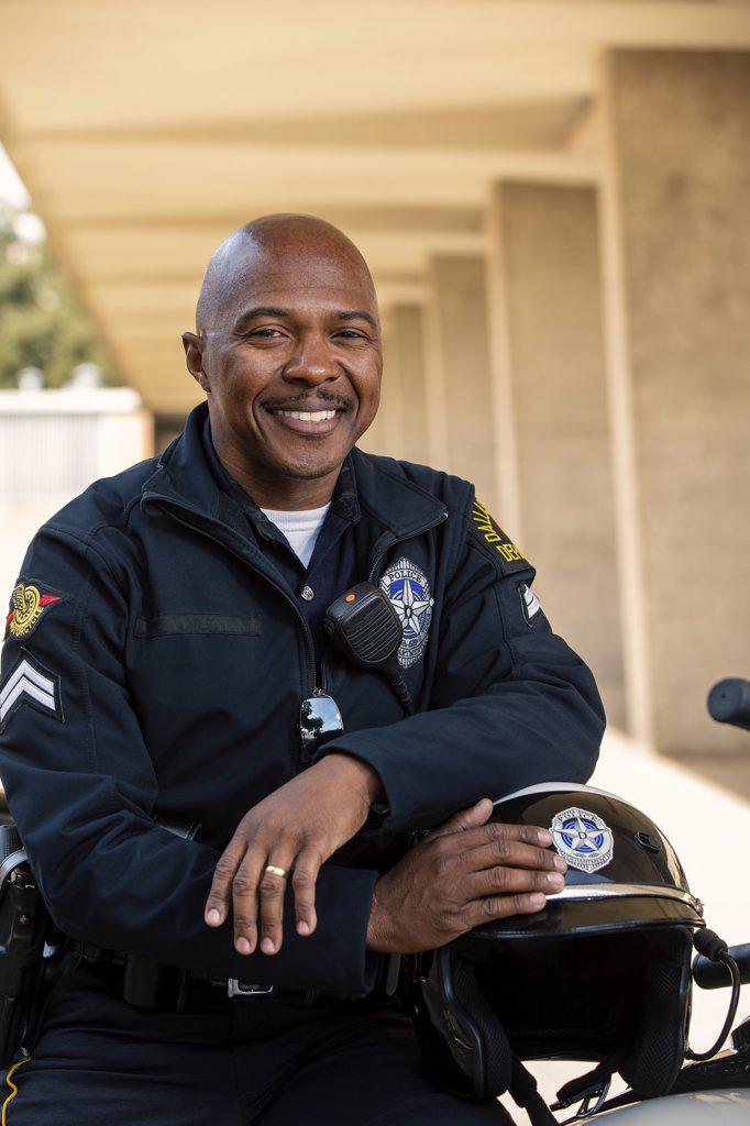 Portrait of Police officer sitting on his motorcycle outside looking towards camera smiling 