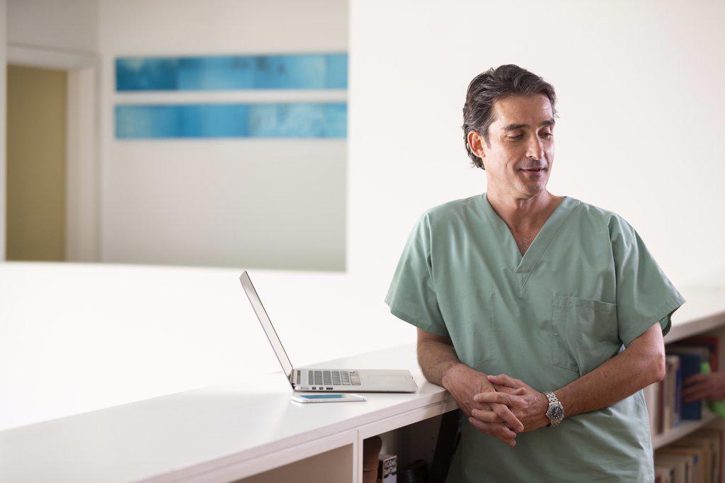 Portrait of Hispanic Male doctor in his home taking a break from practicing Tele-medicine, looking off camera 
