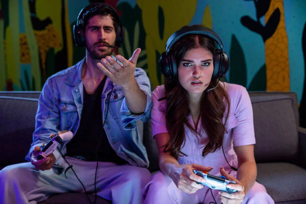 Man and woman playing video games at home wearing headsets.