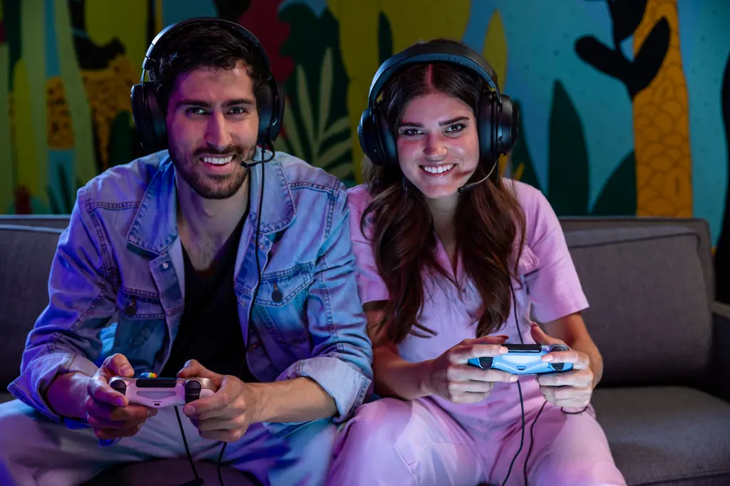 Excited friends playing video game together at home wearing microphone headsets.