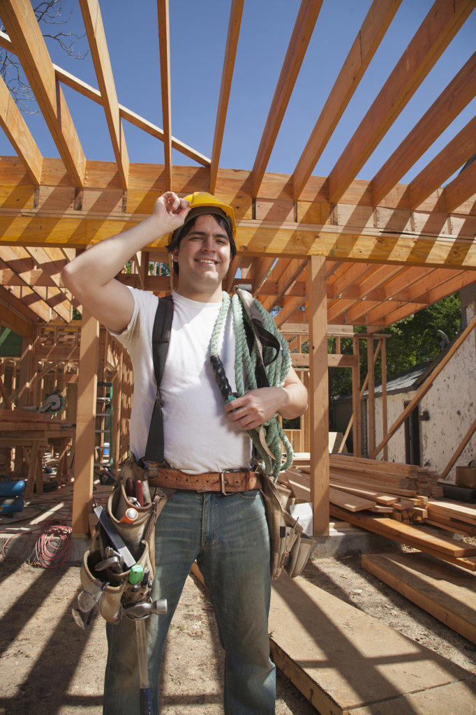 Portrait of a construction worker wearing a hard hat and a tool belt while standing on the construction site