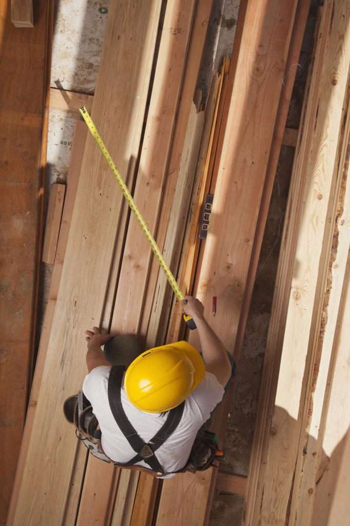 Aerial view of a man measuring wood on a residential construction site