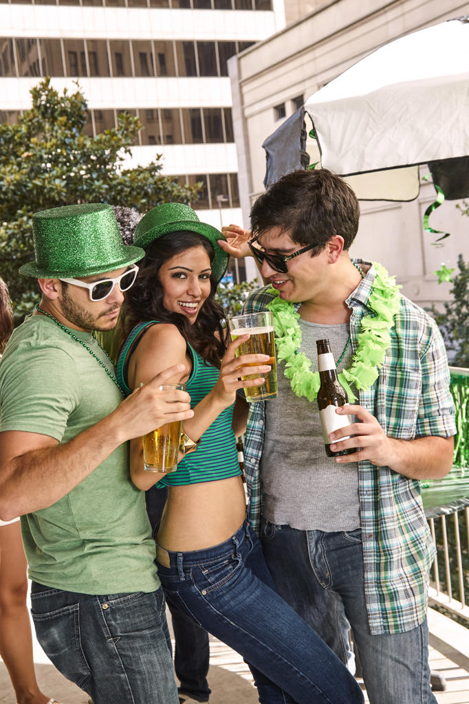 Group of three friends partying together on balcony during St Patrick's Day Parade.