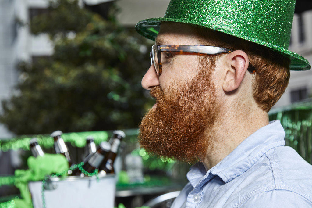 Redhead with beard wearing a green glitter sparkle hat at St. Patrick's Day party. 