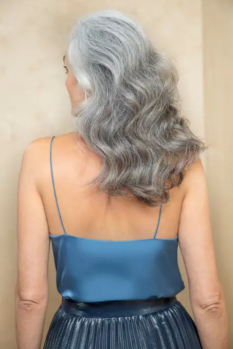 Medium close up of a middle-aged woman with grey hair turned away from camera.