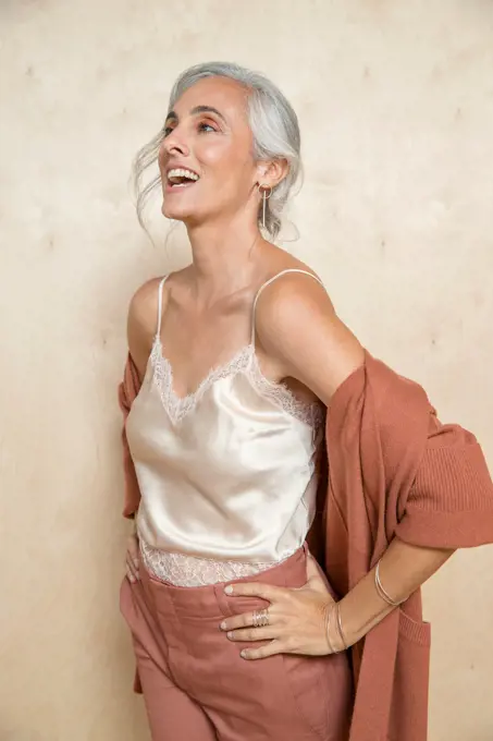 Youthful woman with gray hair looks off camera and laughs.