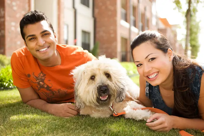 Couple with dog laying on grass