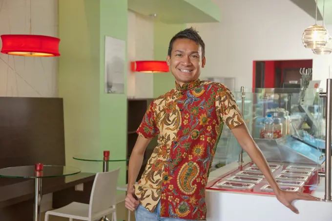Smiling Malaysian man standing in cafe