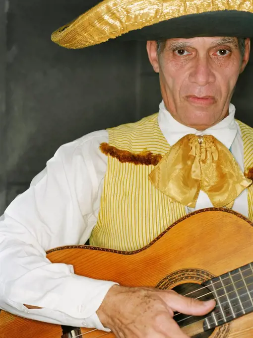 Senior man in traditional clothing playing guitar