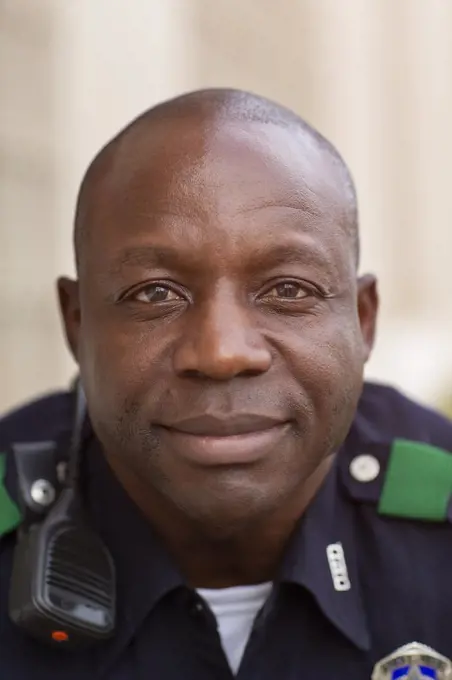 Close up Portrait of uniformed Police officer sitting outside looking towards camera smiling 
