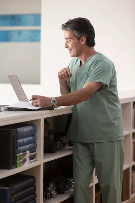 Hispanic Male doctor in his home practicing Telemedicine, having video call consultation on laptop 