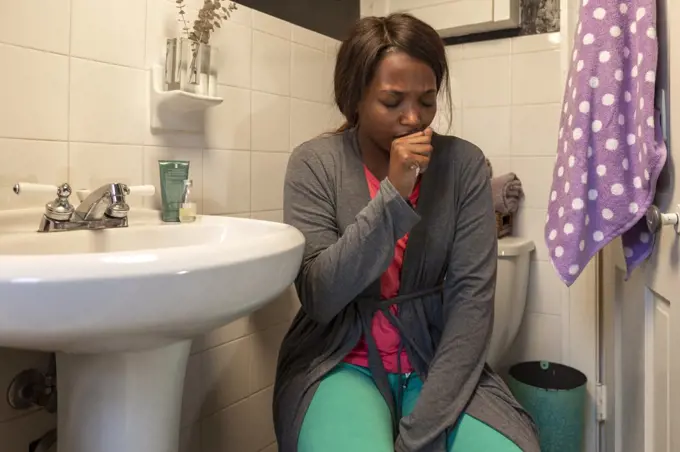 Young coughing woman in the bathroom feeling ill 