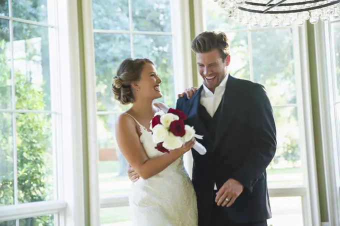 Bride and Groom walking into reception,  laughing and looking down, bride holding bouquet 