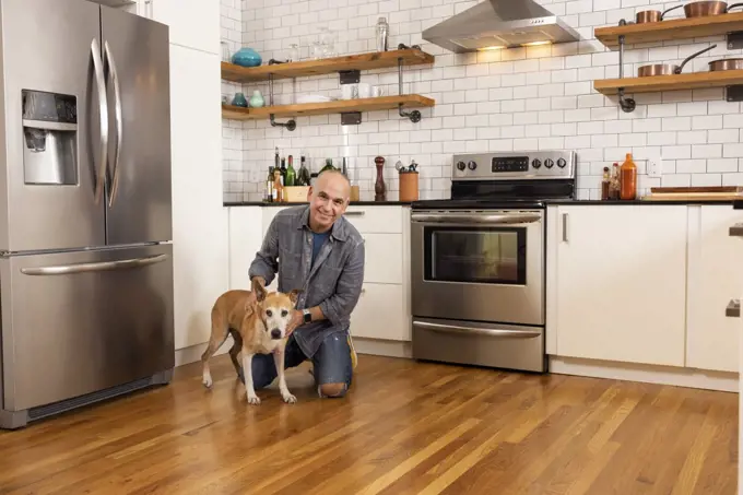 Low angle portrait of man and his pet together in kitchen.